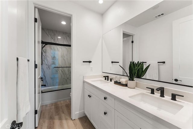 full bathroom featuring vanity, toilet, wood-type flooring, and bath / shower combo with glass door