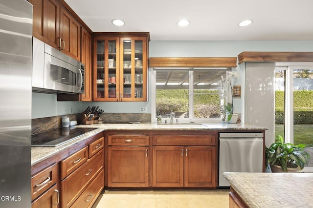 kitchen featuring light tile patterned floors, light stone countertops, stainless steel appliances, and sink