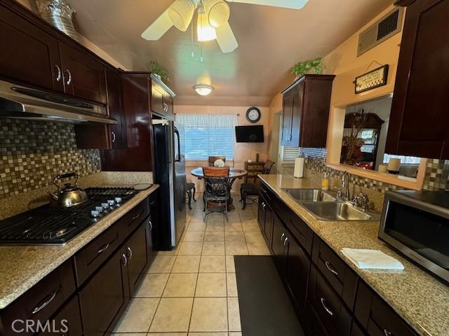 kitchen with decorative backsplash, ceiling fan, sink, and stainless steel appliances