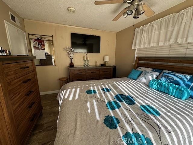 bedroom with a textured ceiling, ceiling fan, and dark wood-type flooring