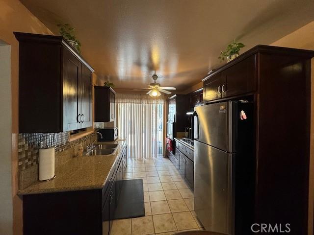 kitchen featuring dark brown cabinetry, ceiling fan, sink, stainless steel appliances, and decorative backsplash