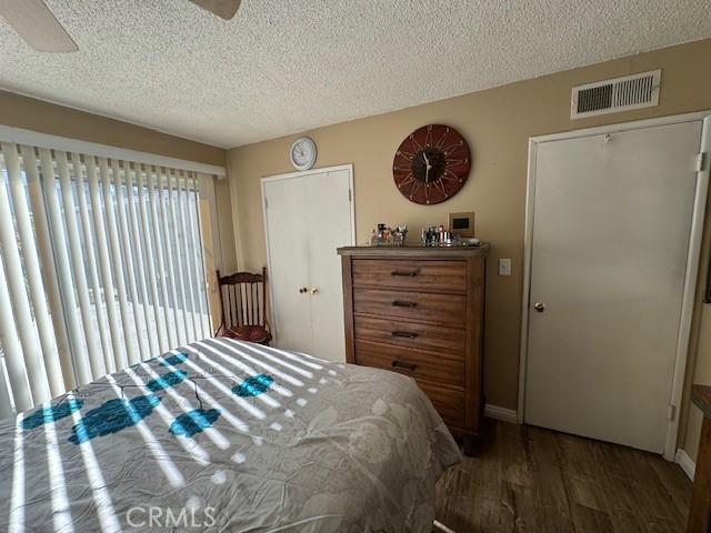 bedroom featuring a textured ceiling, ceiling fan, and dark wood-type flooring