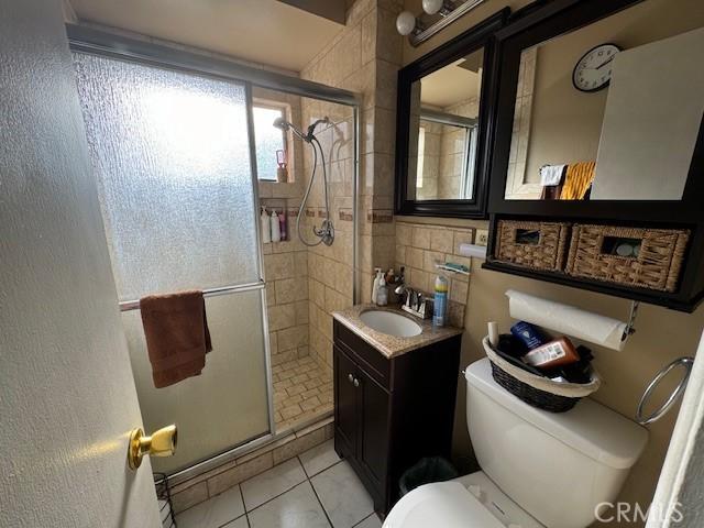 bathroom featuring tile patterned floors, vanity, toilet, and a shower with door