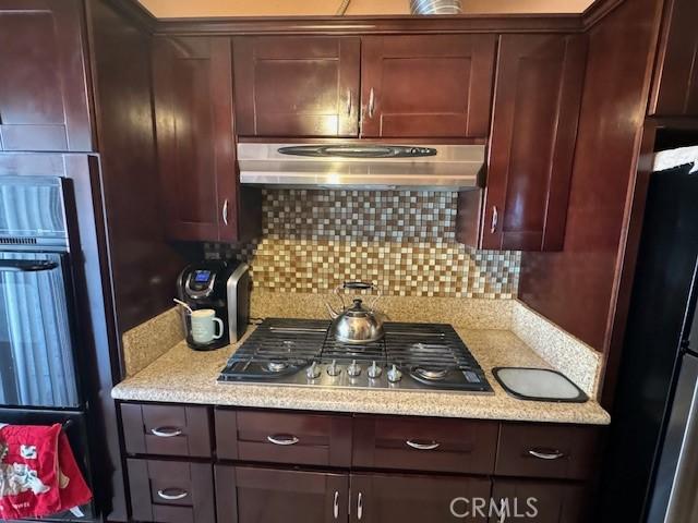 kitchen featuring decorative backsplash, stainless steel appliances, and light stone counters