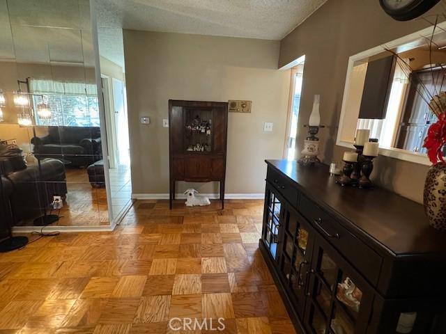 corridor with light parquet flooring and a textured ceiling