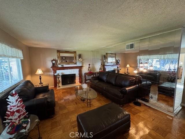 living room with a textured ceiling, parquet floors, and a healthy amount of sunlight