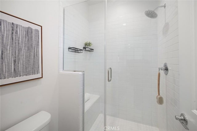 bathroom featuring toilet and a shower with shower door