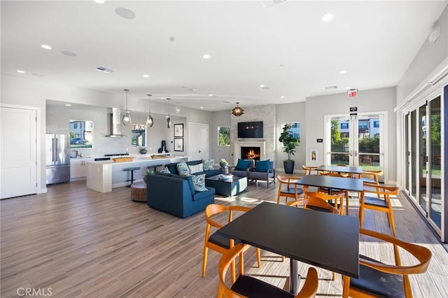 dining space with hardwood / wood-style flooring, a large fireplace, and french doors