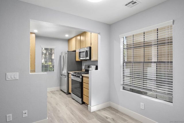 kitchen with light hardwood / wood-style floors, light brown cabinets, and appliances with stainless steel finishes