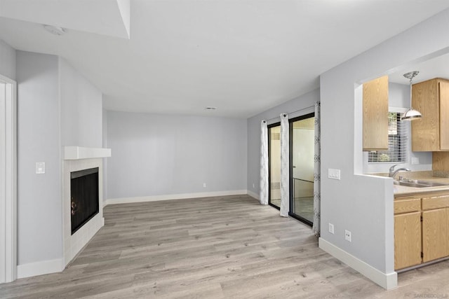 unfurnished living room featuring light wood-type flooring, a large fireplace, and sink