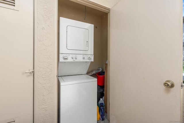 clothes washing area featuring stacked washer / drying machine