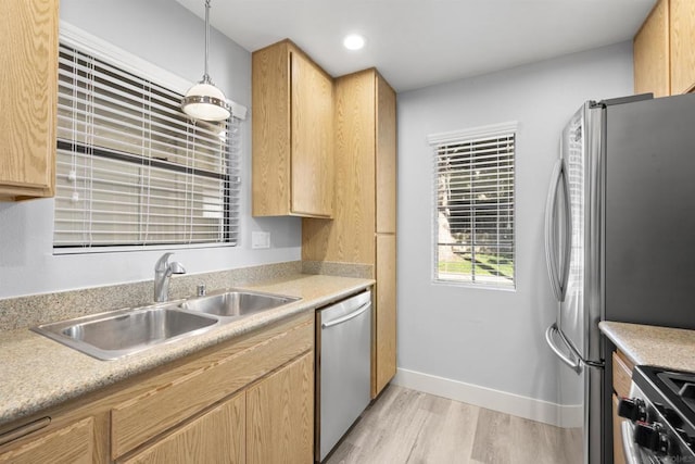 kitchen with light brown cabinets, sink, stainless steel appliances, light hardwood / wood-style flooring, and decorative light fixtures