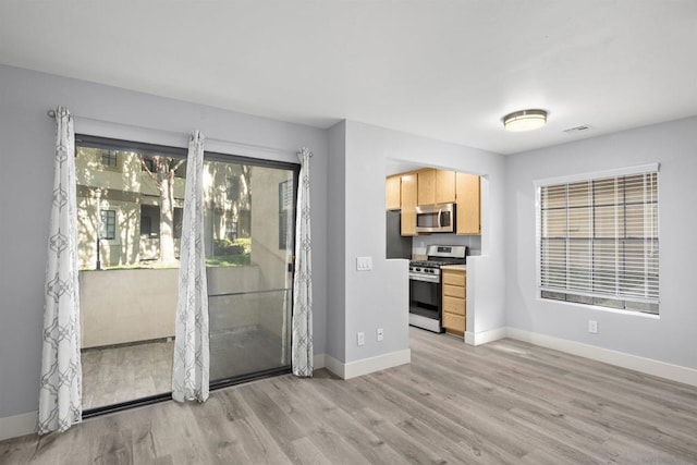 interior space with light brown cabinets, appliances with stainless steel finishes, and light hardwood / wood-style flooring