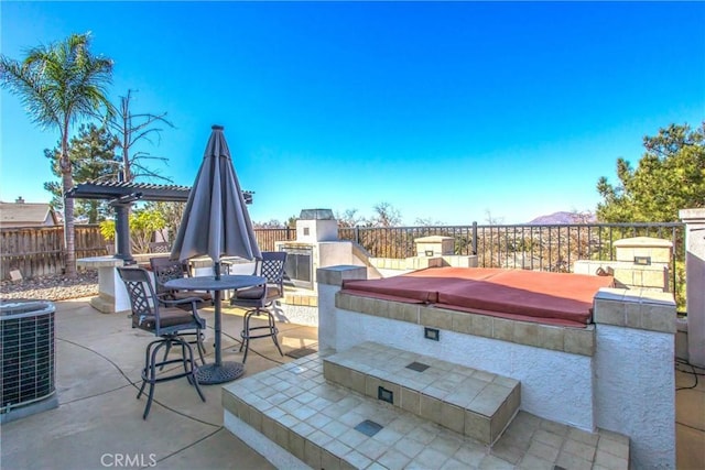 view of patio / terrace featuring central AC, exterior fireplace, and a hot tub