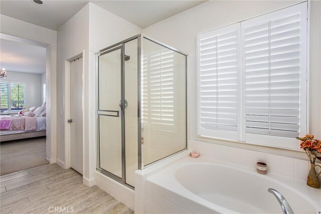 bathroom featuring hardwood / wood-style floors, shower with separate bathtub, and a notable chandelier