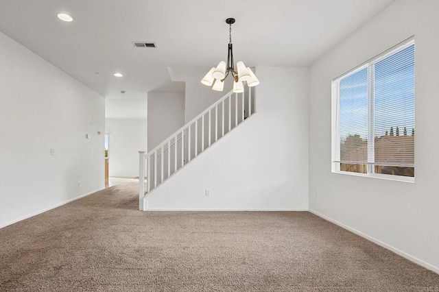 empty room with a notable chandelier and carpet flooring