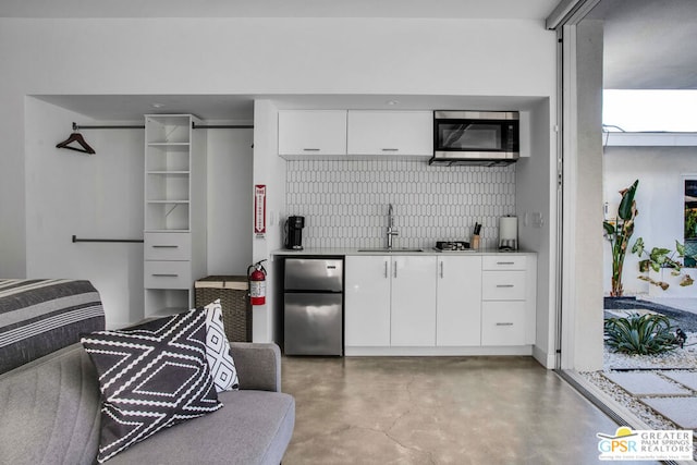 kitchen with white cabinetry, sink, concrete flooring, and appliances with stainless steel finishes