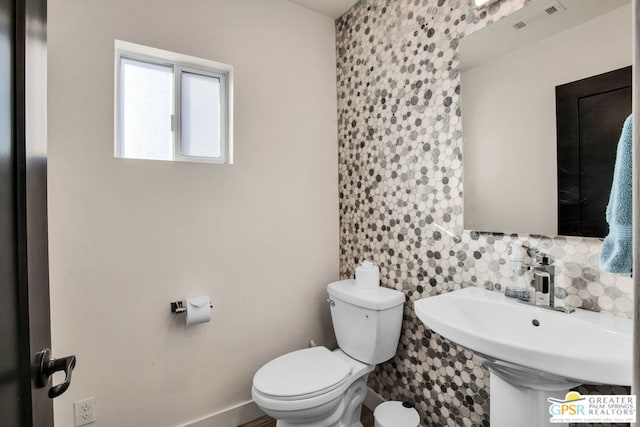 bathroom featuring sink, tile walls, and toilet