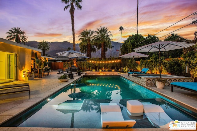 pool at dusk featuring a mountain view and a patio area