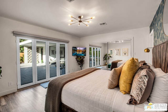 bedroom with access to outside, hardwood / wood-style floors, a chandelier, and french doors