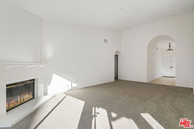 unfurnished living room featuring a fireplace and light colored carpet