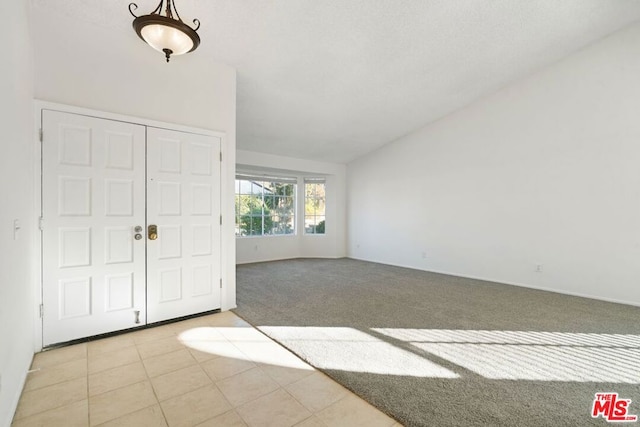 carpeted foyer featuring lofted ceiling