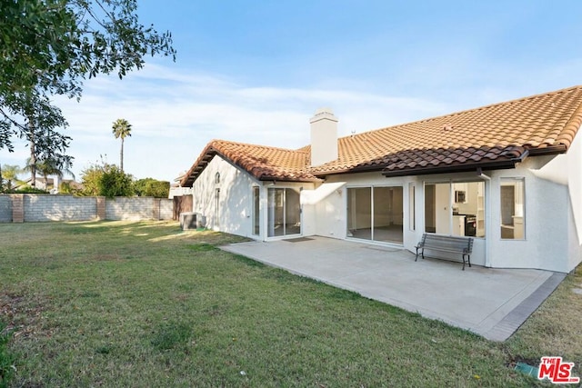 rear view of property featuring cooling unit, a yard, and a patio