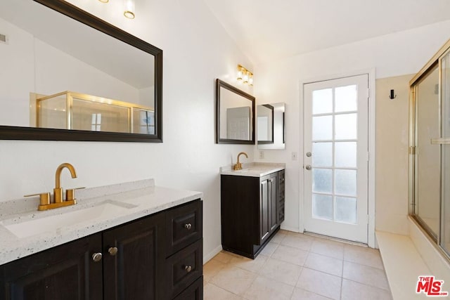 bathroom with tile patterned flooring, vanity, vaulted ceiling, and walk in shower