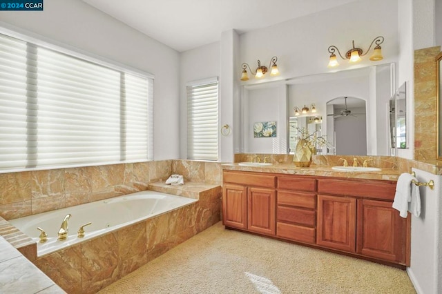 bathroom featuring tiled tub, ceiling fan, and vanity