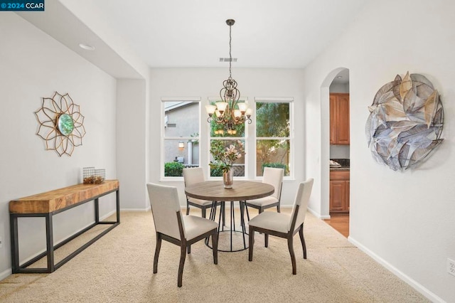 carpeted dining area featuring an inviting chandelier