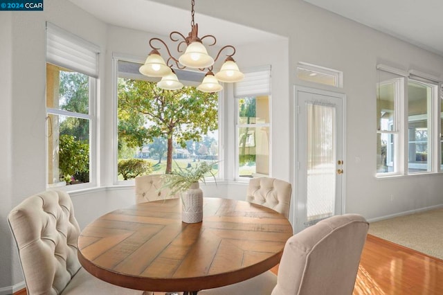 dining space with carpet flooring, a healthy amount of sunlight, and an inviting chandelier