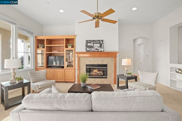 carpeted living room with ceiling fan and a tiled fireplace