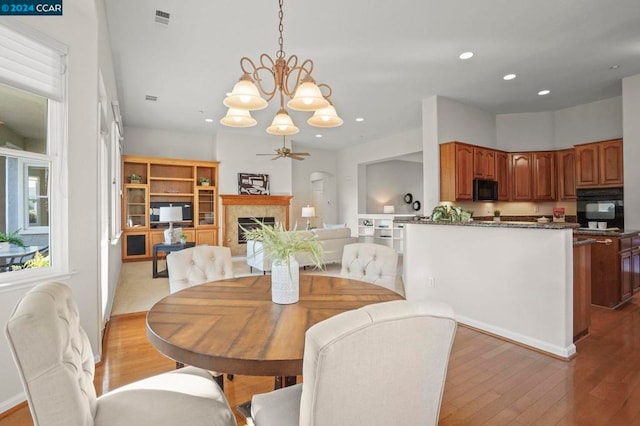 dining area featuring ceiling fan with notable chandelier and light hardwood / wood-style floors