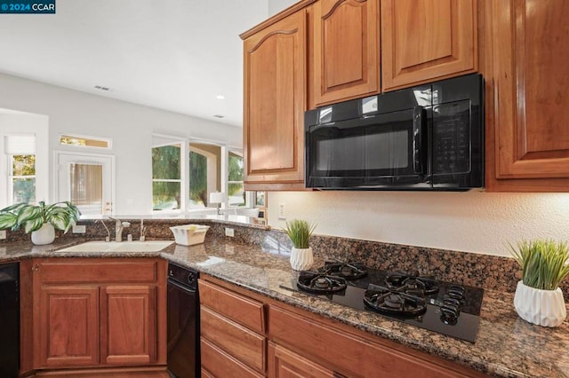 kitchen featuring black appliances, sink, and dark stone counters