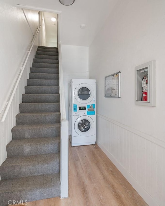 stairs featuring wood-type flooring and stacked washing maching and dryer