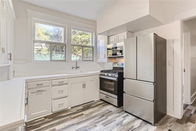 kitchen with white cabinets, sink, light wood-type flooring, and stainless steel appliances