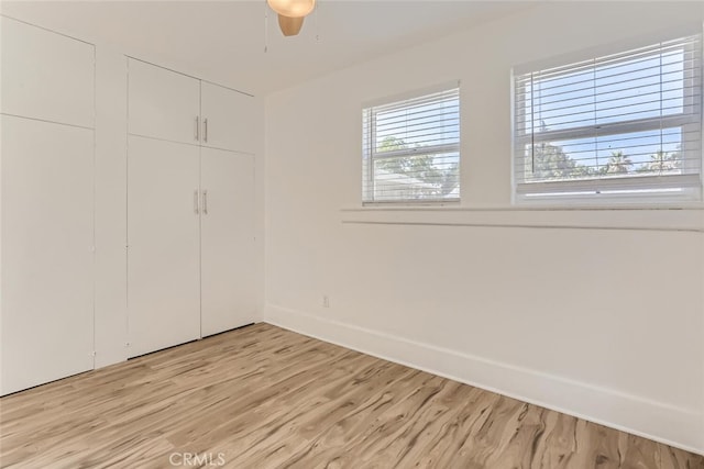 unfurnished bedroom with ceiling fan and light wood-type flooring