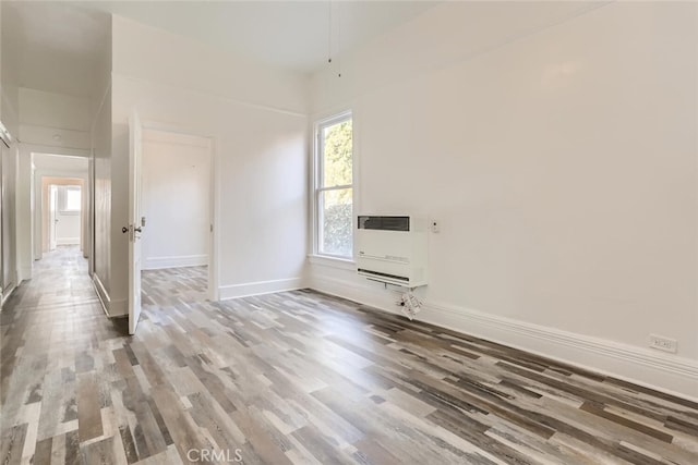 empty room with wood-type flooring and heating unit