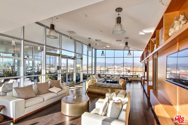 living room with dark hardwood / wood-style floors, a wall of windows, and a high ceiling