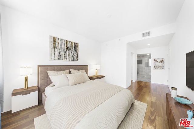 bedroom with connected bathroom and dark hardwood / wood-style flooring