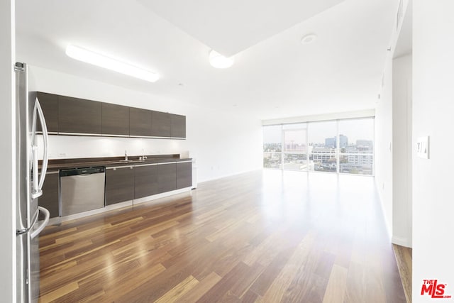 unfurnished living room with sink, expansive windows, and dark wood-type flooring