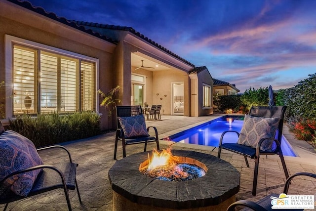 pool at dusk featuring an outdoor fire pit and a patio