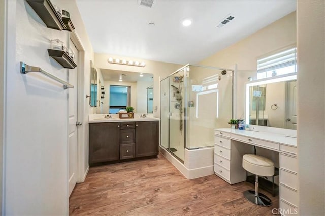 bathroom with wood-type flooring, vanity, and an enclosed shower