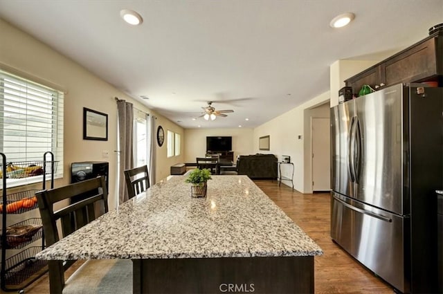 kitchen with stainless steel fridge, a kitchen island, a wealth of natural light, and dark wood-type flooring