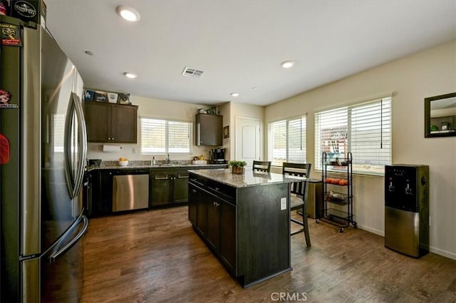 kitchen with a kitchen island, dark brown cabinetry, dark wood-type flooring, and appliances with stainless steel finishes