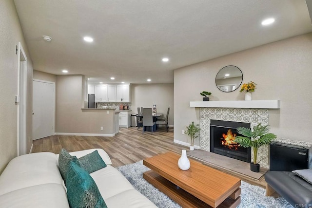 living room featuring light hardwood / wood-style floors and a tiled fireplace