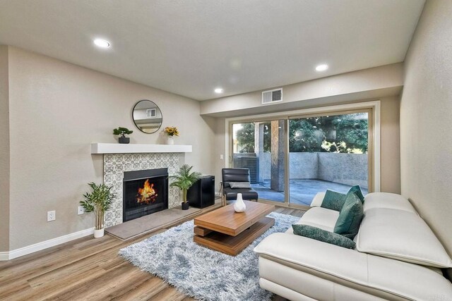 living room with a tiled fireplace and hardwood / wood-style floors