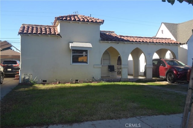 mediterranean / spanish-style home featuring a carport, covered porch, and a front lawn