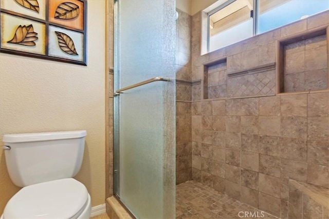 bathroom featuring toilet and a shower with shower door