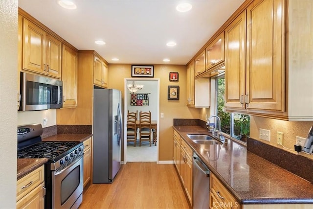 kitchen featuring dark stone countertops, light wood-type flooring, sink, and appliances with stainless steel finishes